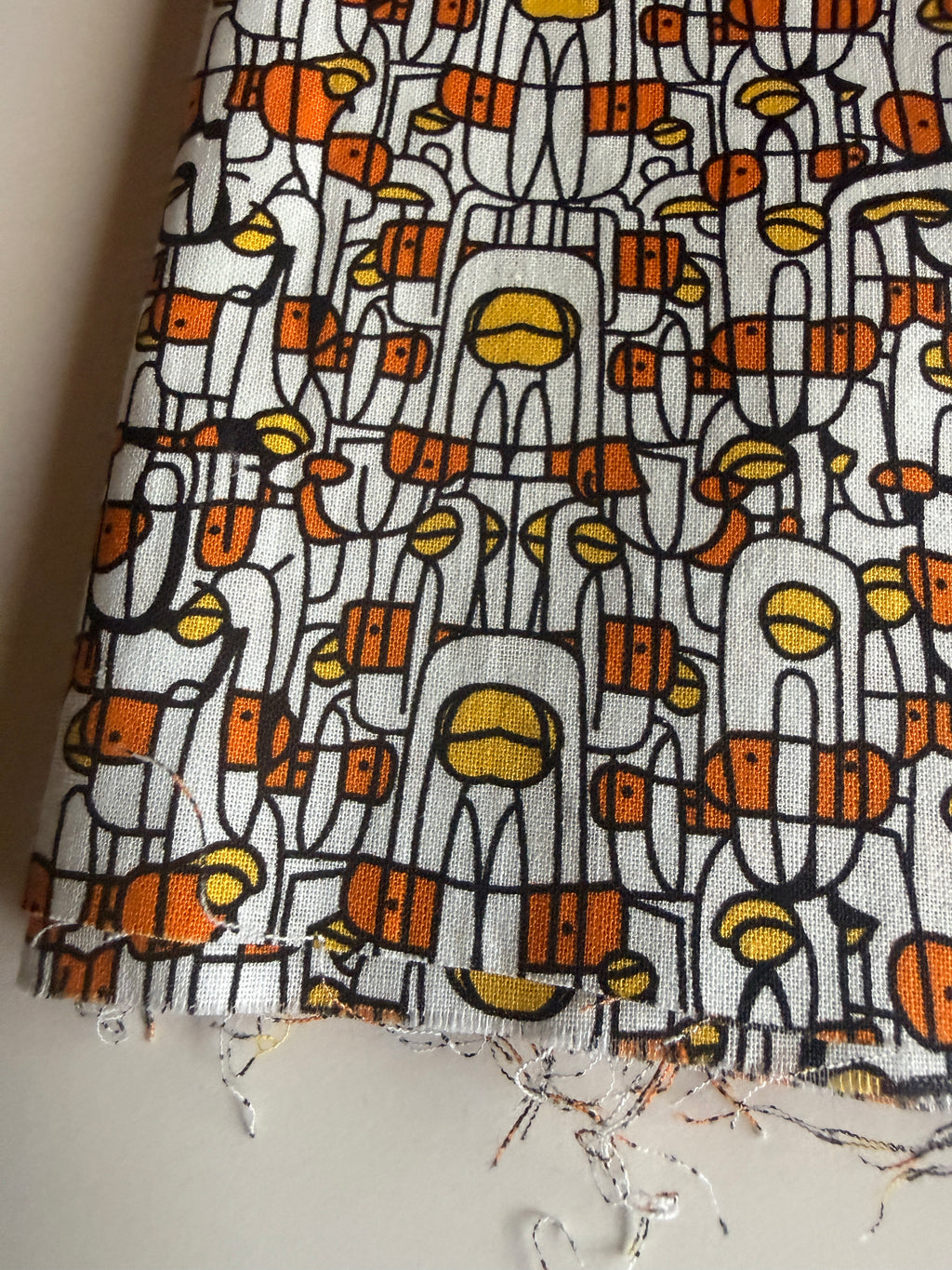 Abstract print stylized human figures in orange, yellow, and black cotton