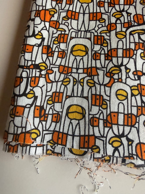 Abstract print stylized human figures in orange, yellow, and black cotton